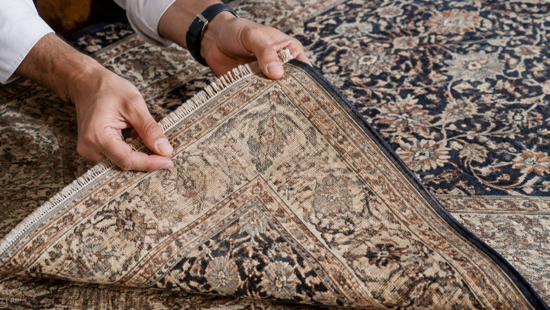 Hands lifting the corner of a Persian-style rug to inspect its front and reverse